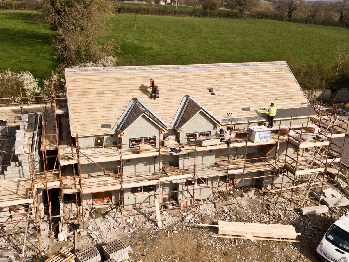 House roofing project with scaffolding and workers on the roof deck